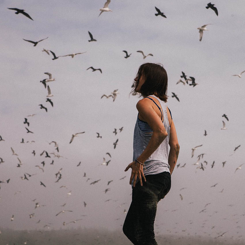 Woman walking on a beach with birds flying